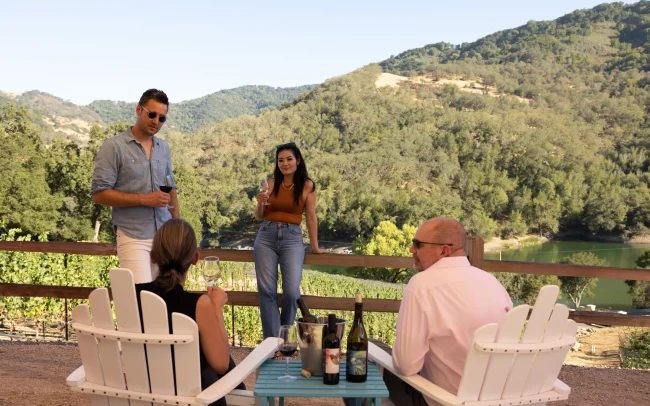 A group of friends enjoying an outdoor wine tasting at Alamitos Vineyards with hillside views