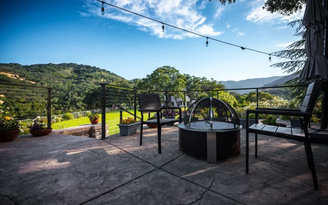 Fire pit and string lights with a view of the lawn and hillside