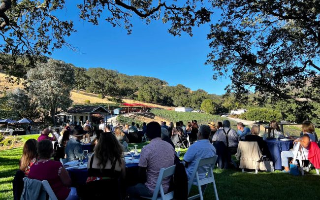 Large group of people seated at outdoor tables on a sunny day at the best Winery in the San Jose area