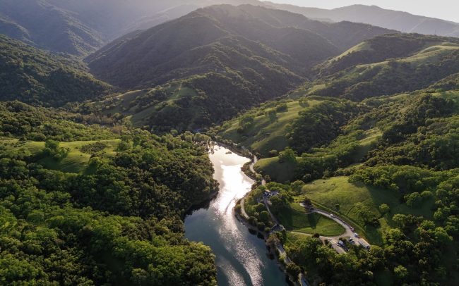 Aerial view of a river running through green hills and mountains